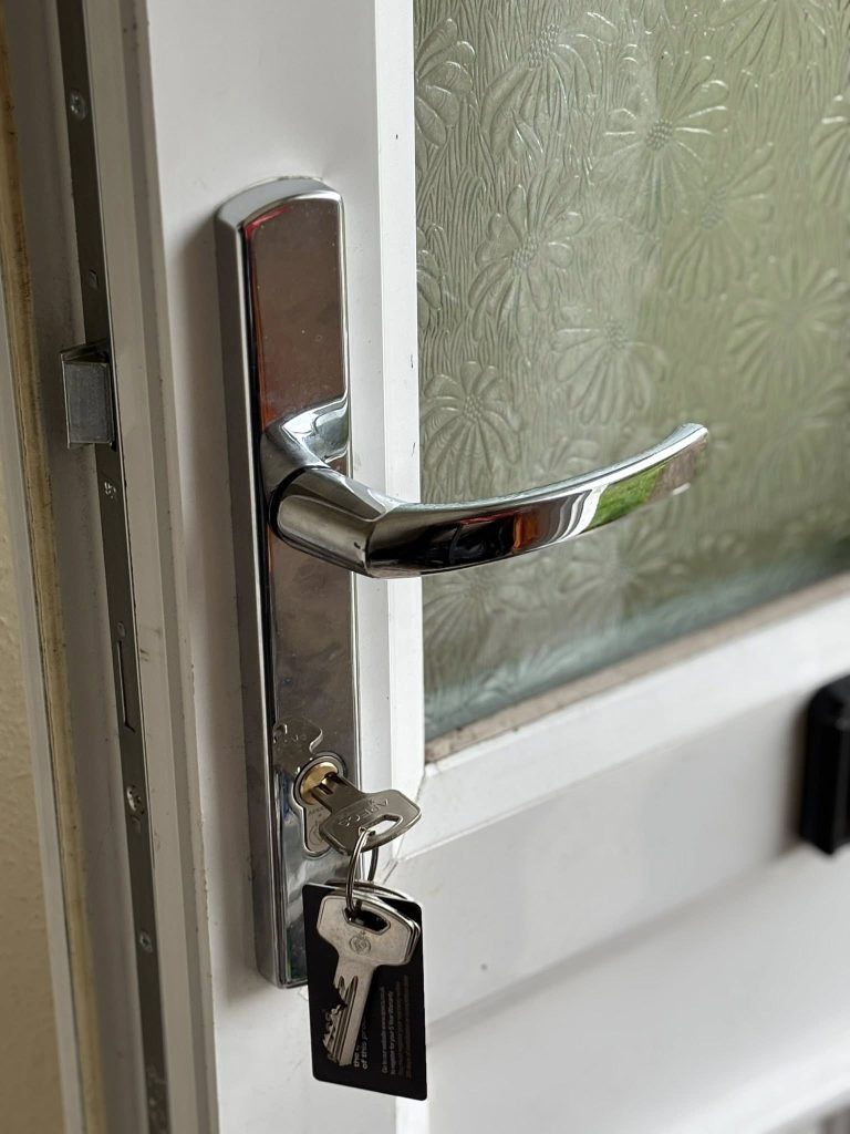 A close-up of a multipoint locking unit installed on a door with keys in