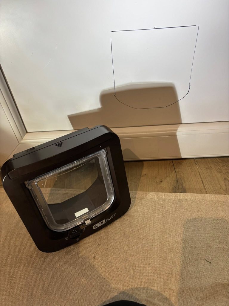 A pet door unit on the floor beside a door with markings